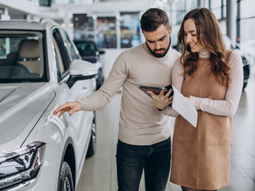 Frau zeigt Mann ein Autoverkauf Angebot auf dem Tablet bei Autoankauf Leverkusen